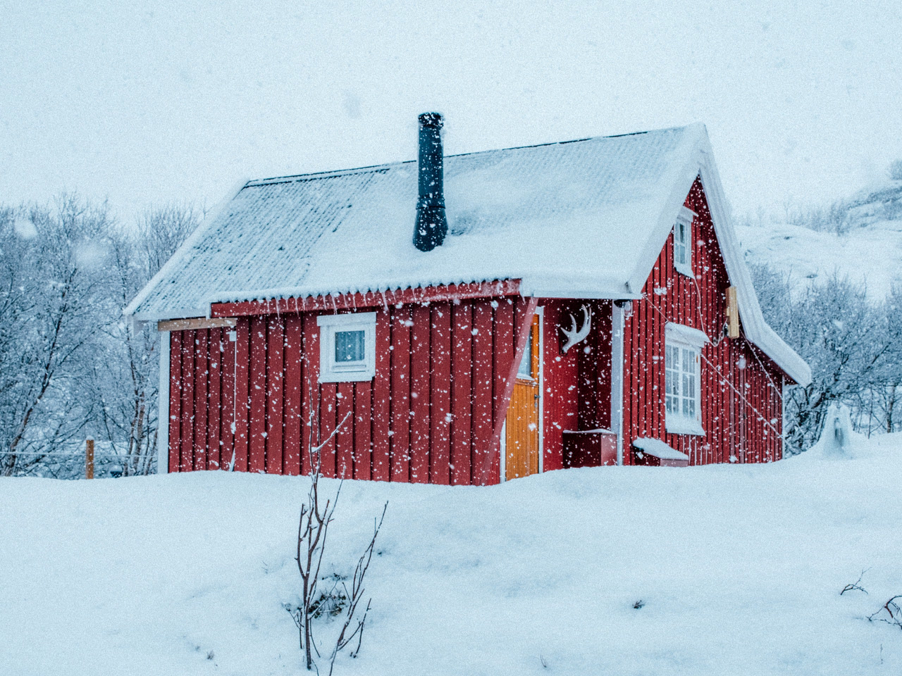 Cabaña roja de pescadores bajo la nevada en un día ártico de Lofoten